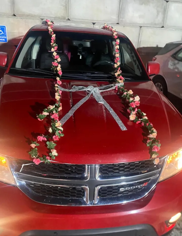 A red SUV with flowers and a silver ribbon across the bonnet, decorated for the day it was handed over.